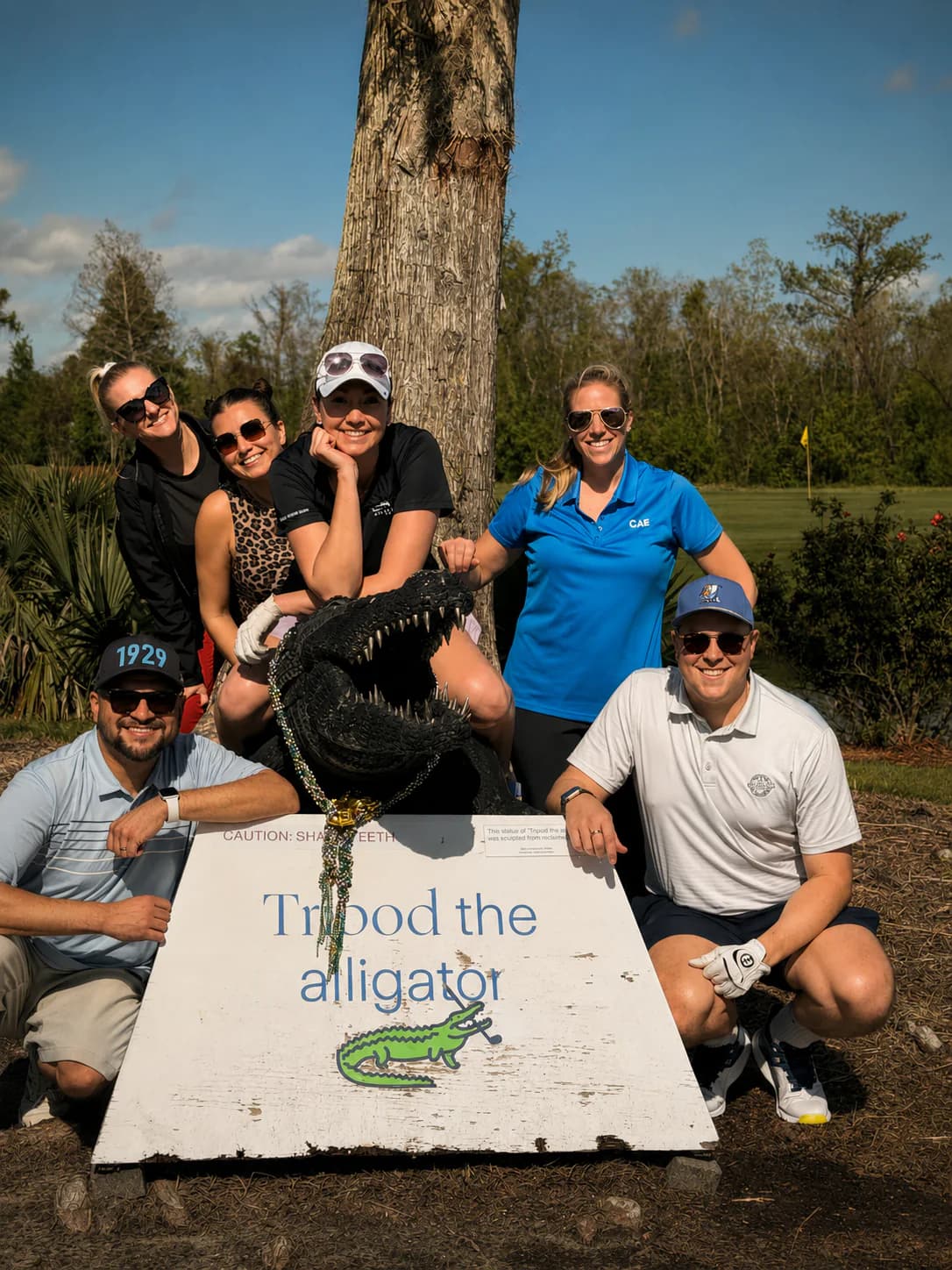 Golfers gathered around the Tripod the alligator sculpture